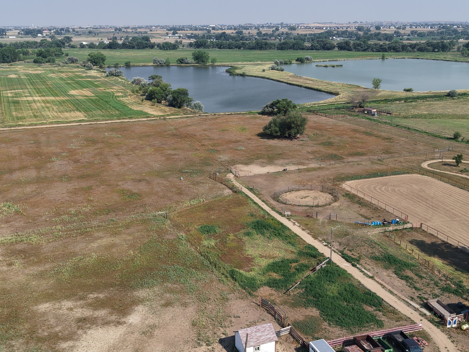 Aerial view of a ranch property with a reservoir, round pen, and riding arena