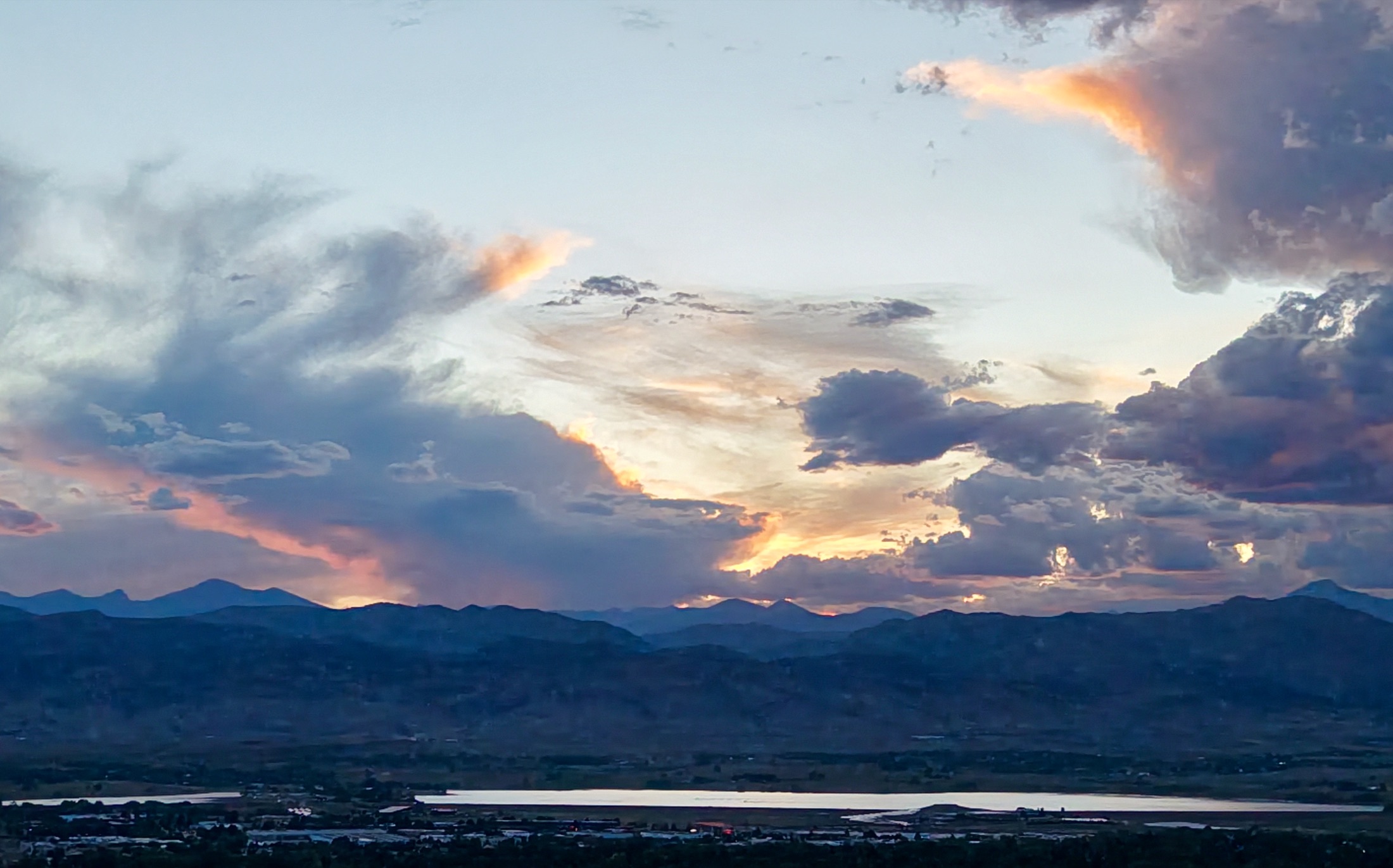 Dramatic storm-cell sunset over the Front Range with a reservoir catching the light