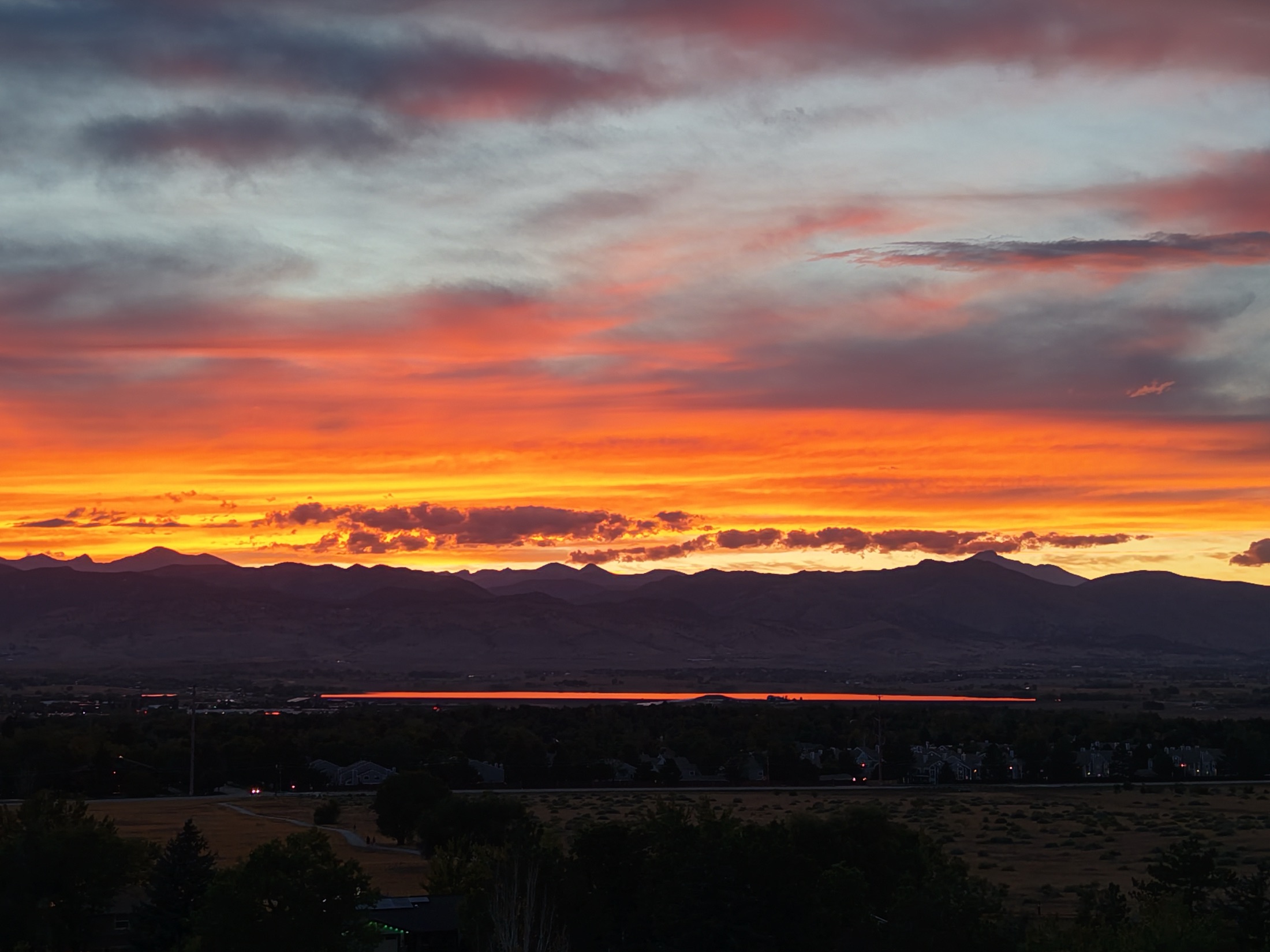 Vivid orange sunset over the Front Range with a red reservoir reflection